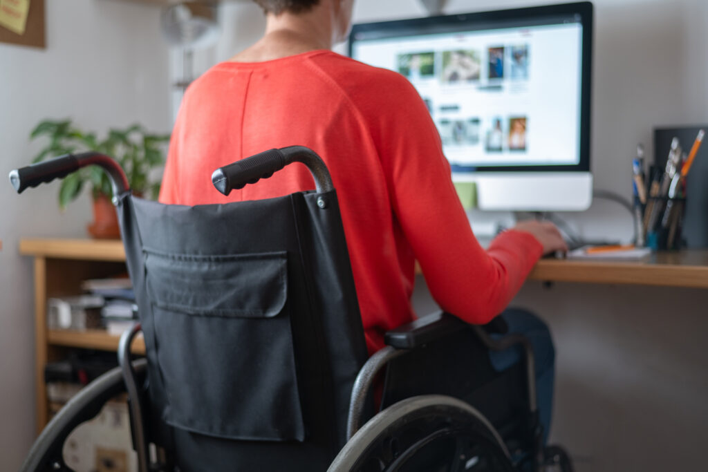 Personne en situation de handicap travaillant à domicile en homeshoring avec poste ergonomique et équipement adapté, incluant Formulaire MDPH pour aménagement.