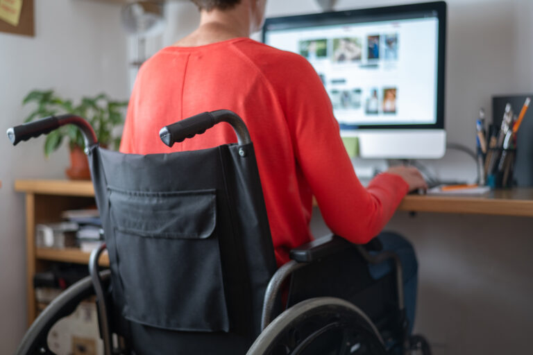Personne en situation de handicap travaillant à domicile en homeshoring avec poste ergonomique et équipement adapté, incluant Formulaire MDPH pour aménagement.